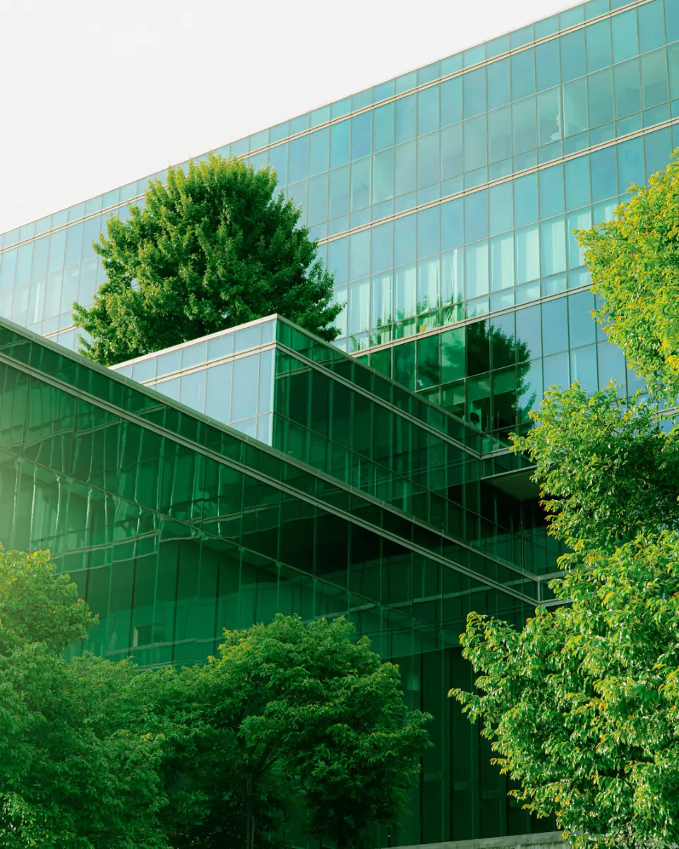 Outside of a green glass building with surrounding trees